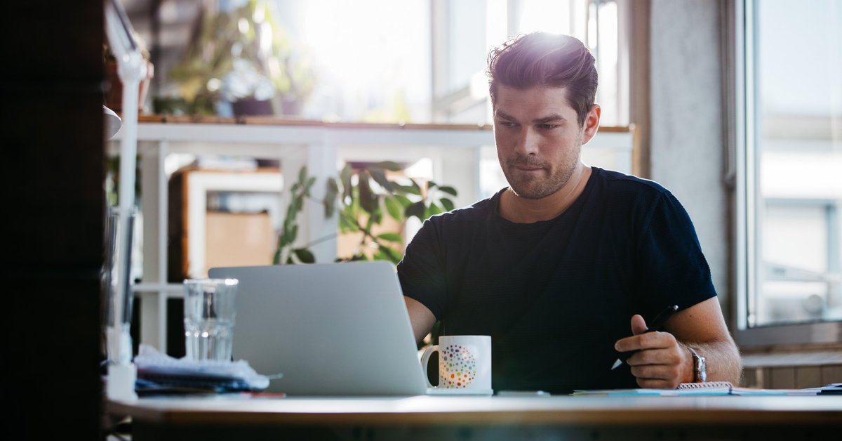 young man sitting at desk using laptop and thinking