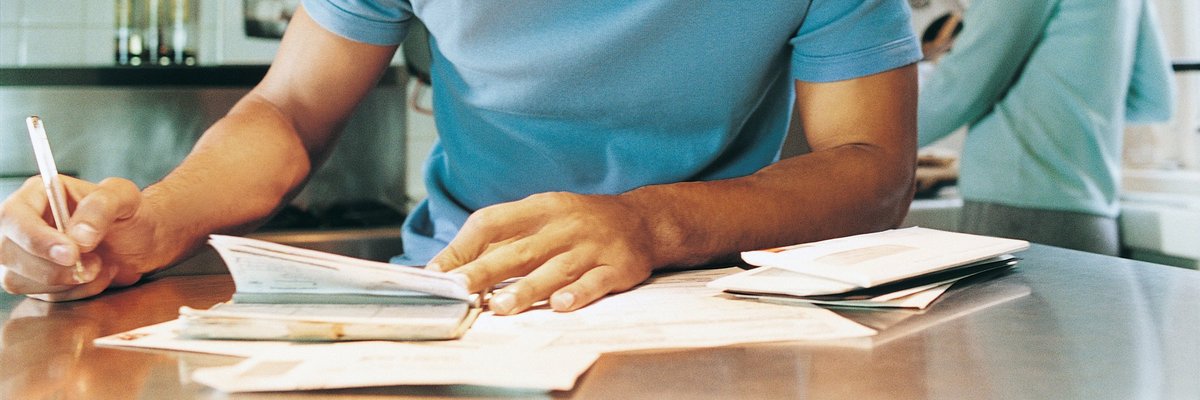 young man sitting at kitchen table writing a check.