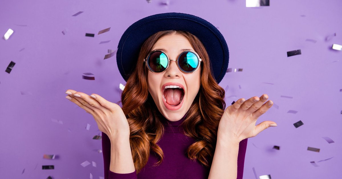 A stylish young woman celebrating and throwing confetti in the air.