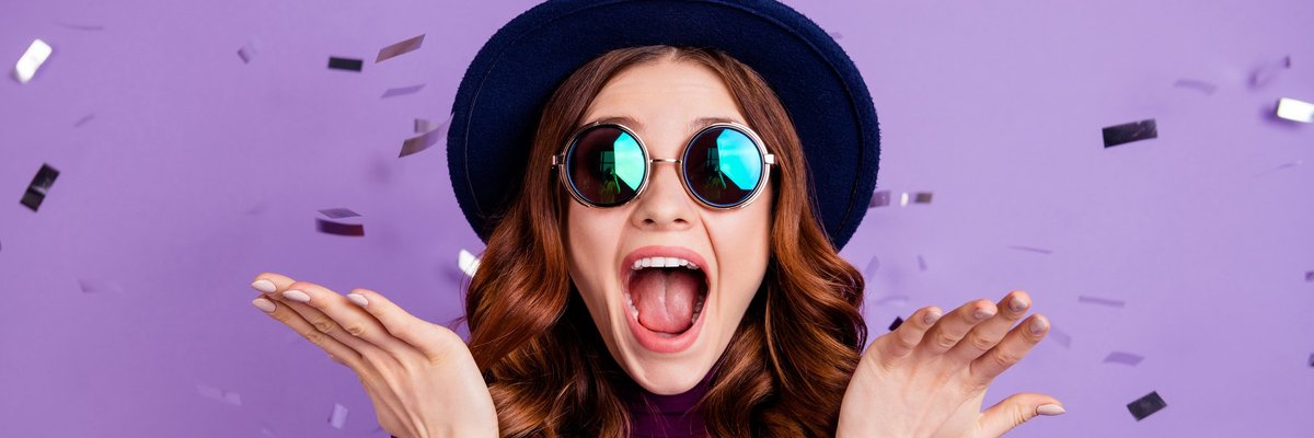 A stylish young woman celebrating and throwing confetti in the air.