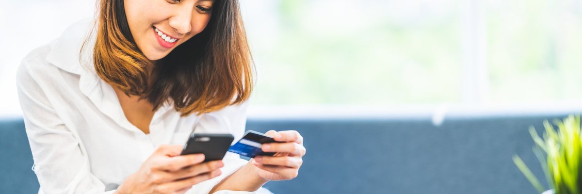 A woman holding a credit card and a cell phone.