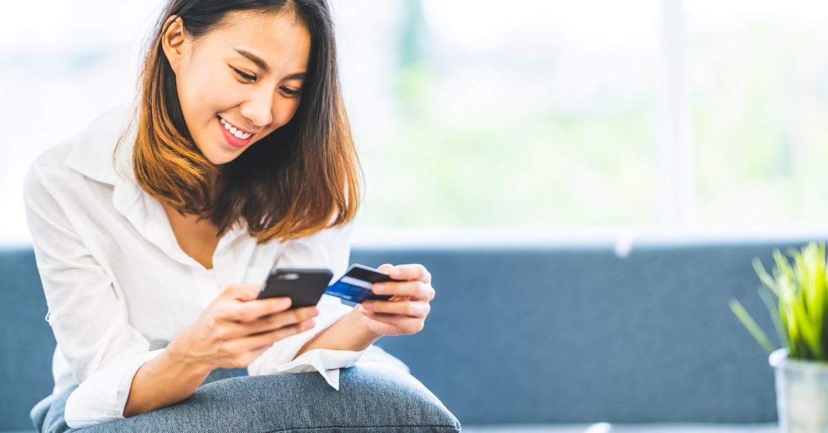 A woman holding a credit card and a cell phone.