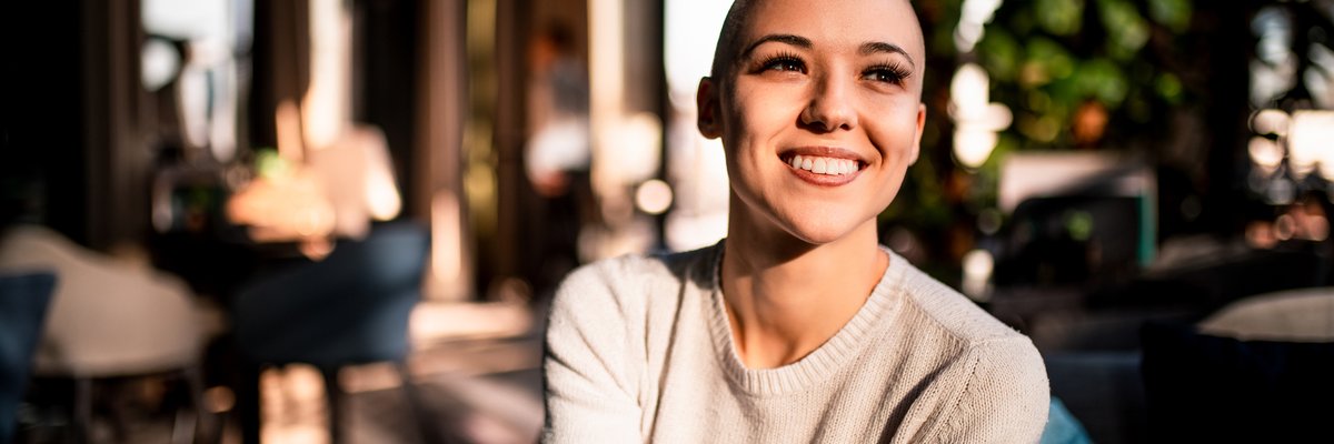 A happy young woman sitting in a sunny room.