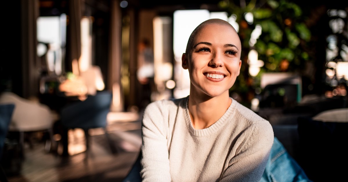 A happy young woman sitting in a sunny room.