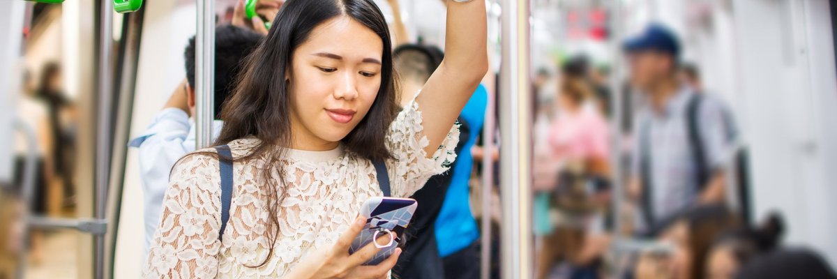 A young woman looking at her phone while riding on the subway.