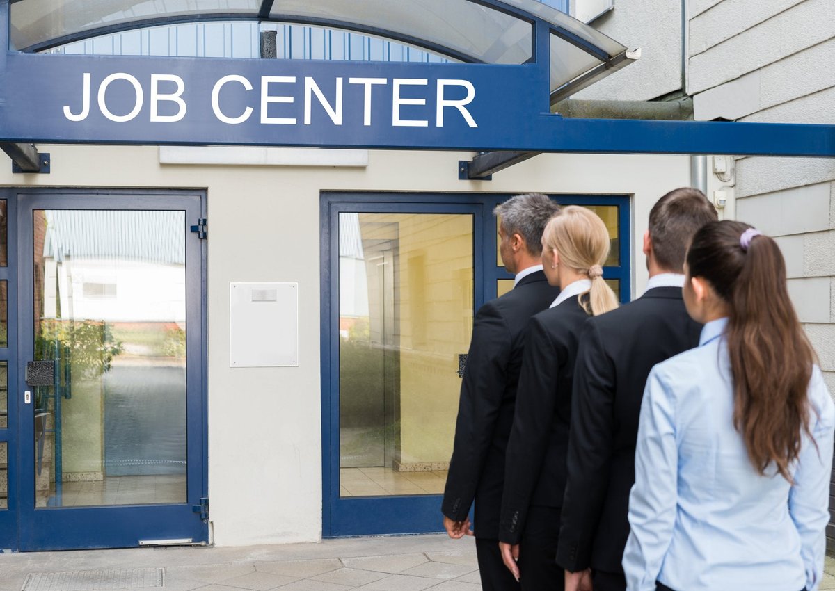 A line of people standing in front of a building labeled Job Center.