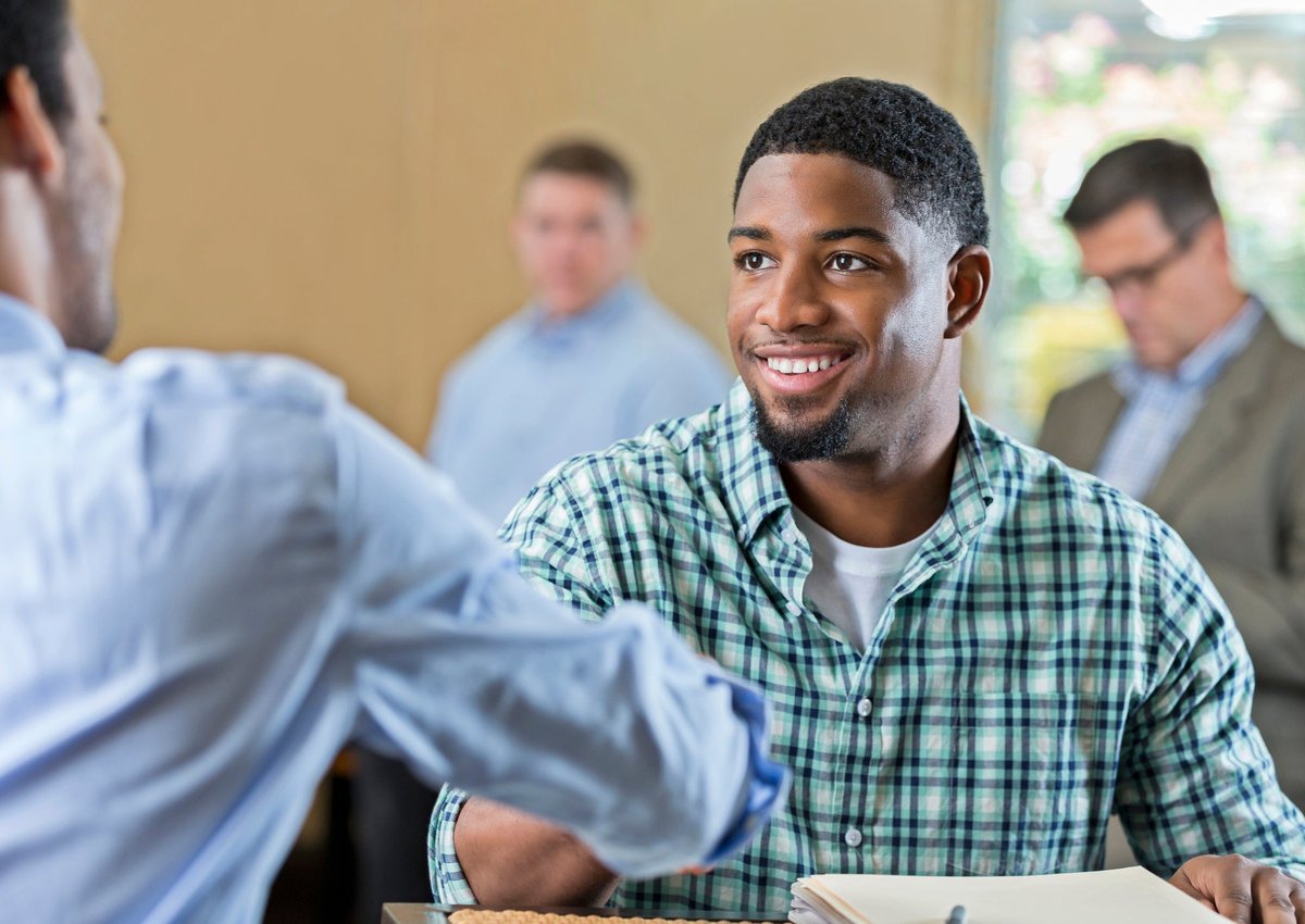 A young man shakes hands with an employer