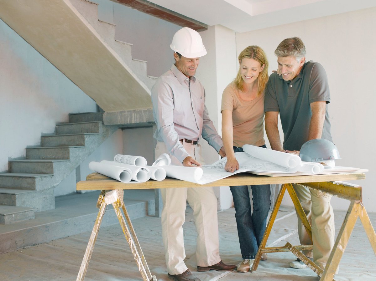 Architect discussing blueprints with couple.