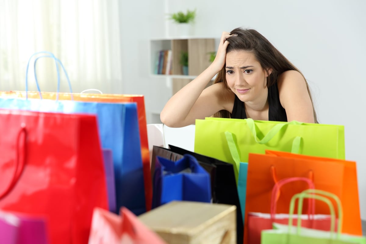 Woman in her home and freaking out as she looks at a bunch of shopping bags.