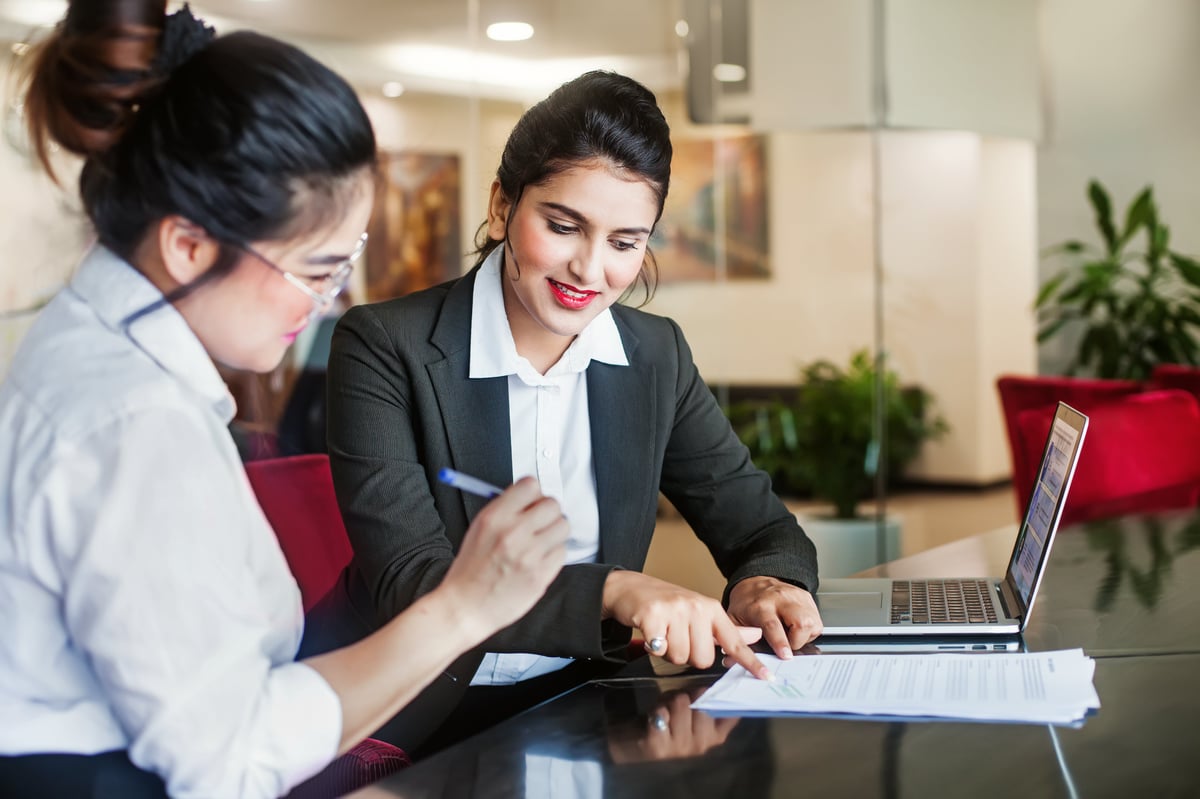A bank employee showing a customer where to sign documents.