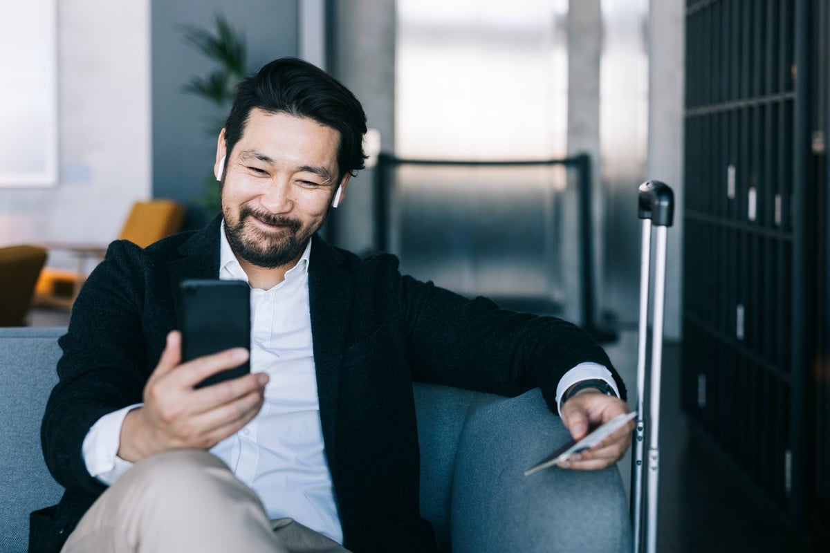A man smiles as he looks at his phone.