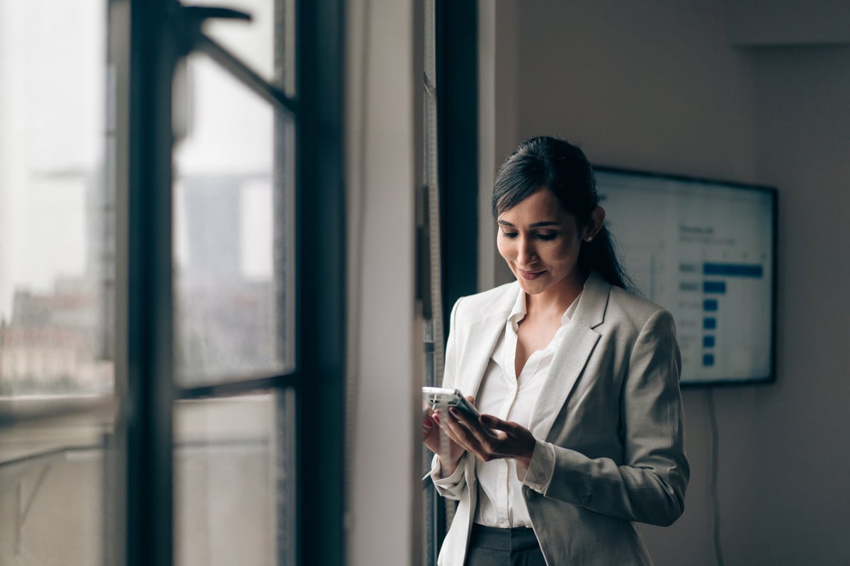 A businesswoman is at the office, on her phone.