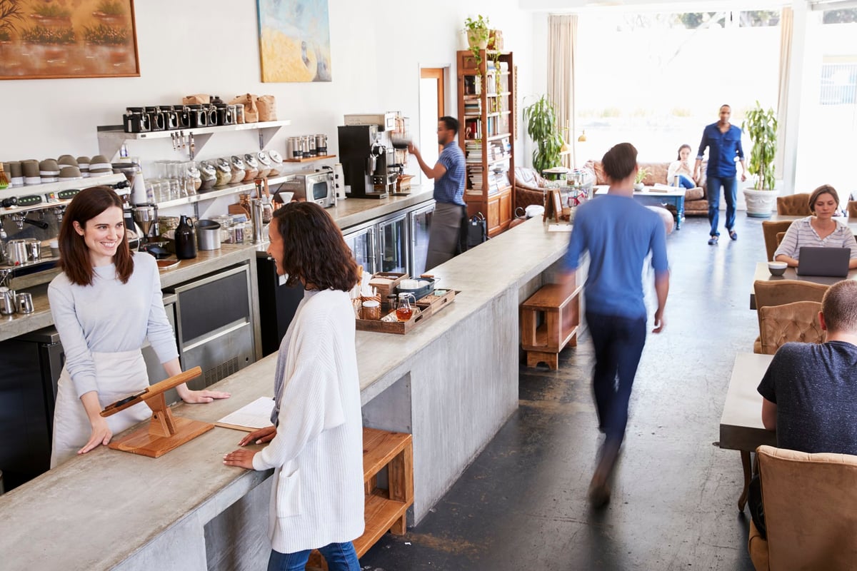 A busy coffee shop with a woman paying at the register.