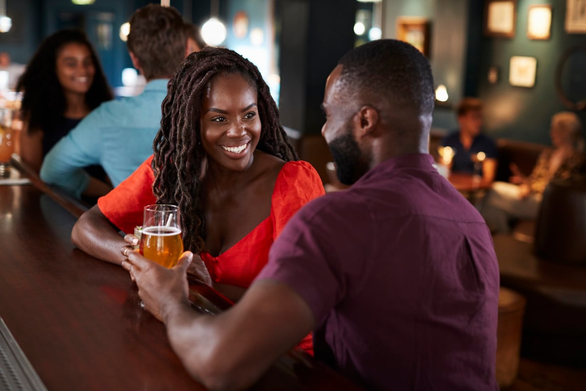 A smiling couple at a bar on a first date.