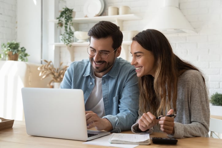 A happy man and woman are looking at a laptop screen.