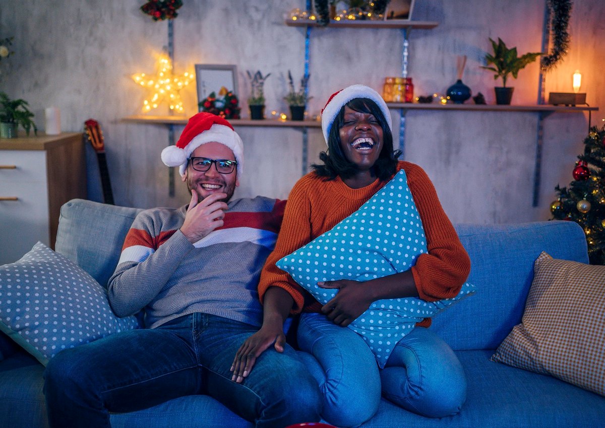 Couple in Santa hats watching a movie on the couch