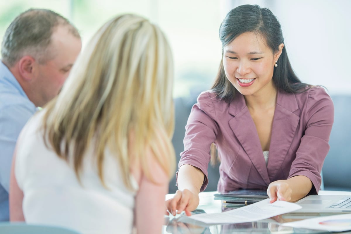 A couple reviews loan documents with a loan officer.