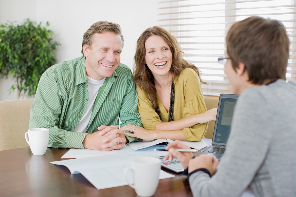 A smiling couple meeting with an advisor.