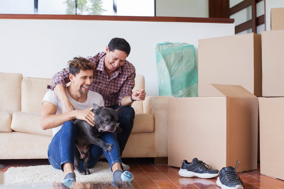 A couple take a break from moving into their new home to play with their dog.