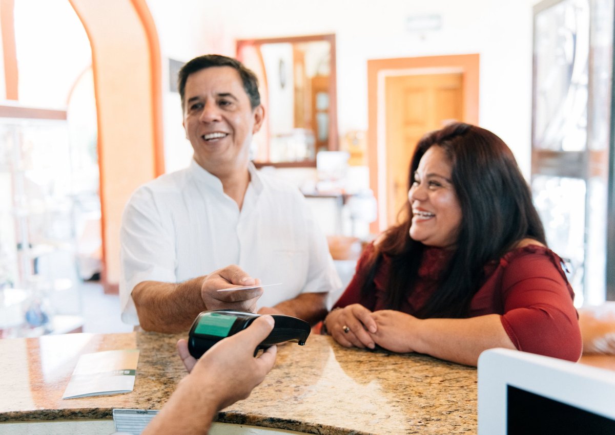 A couple check into a hotel, using a contactless credit card to pay for their stay.
