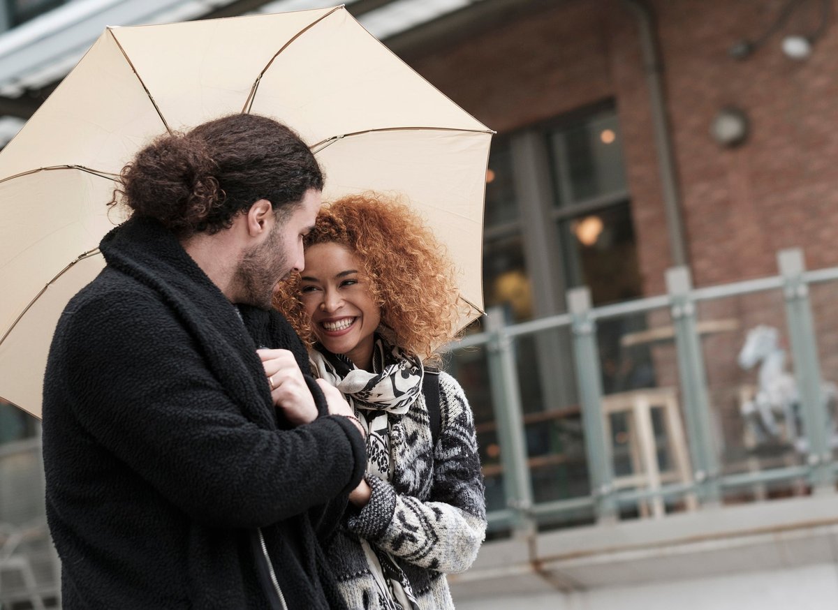 Couple walking through city under umbrella.
