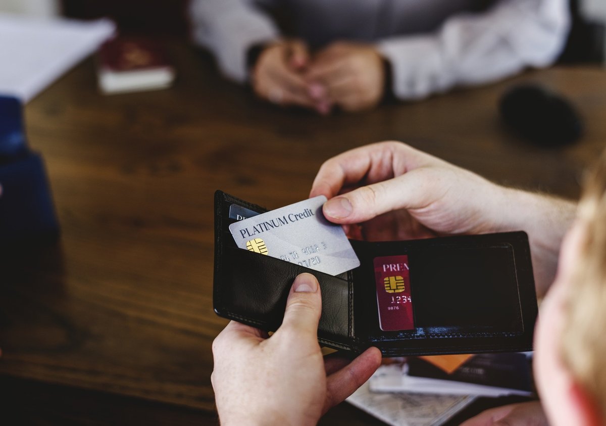 A person taking a credit card out of their wallet to pay for something.