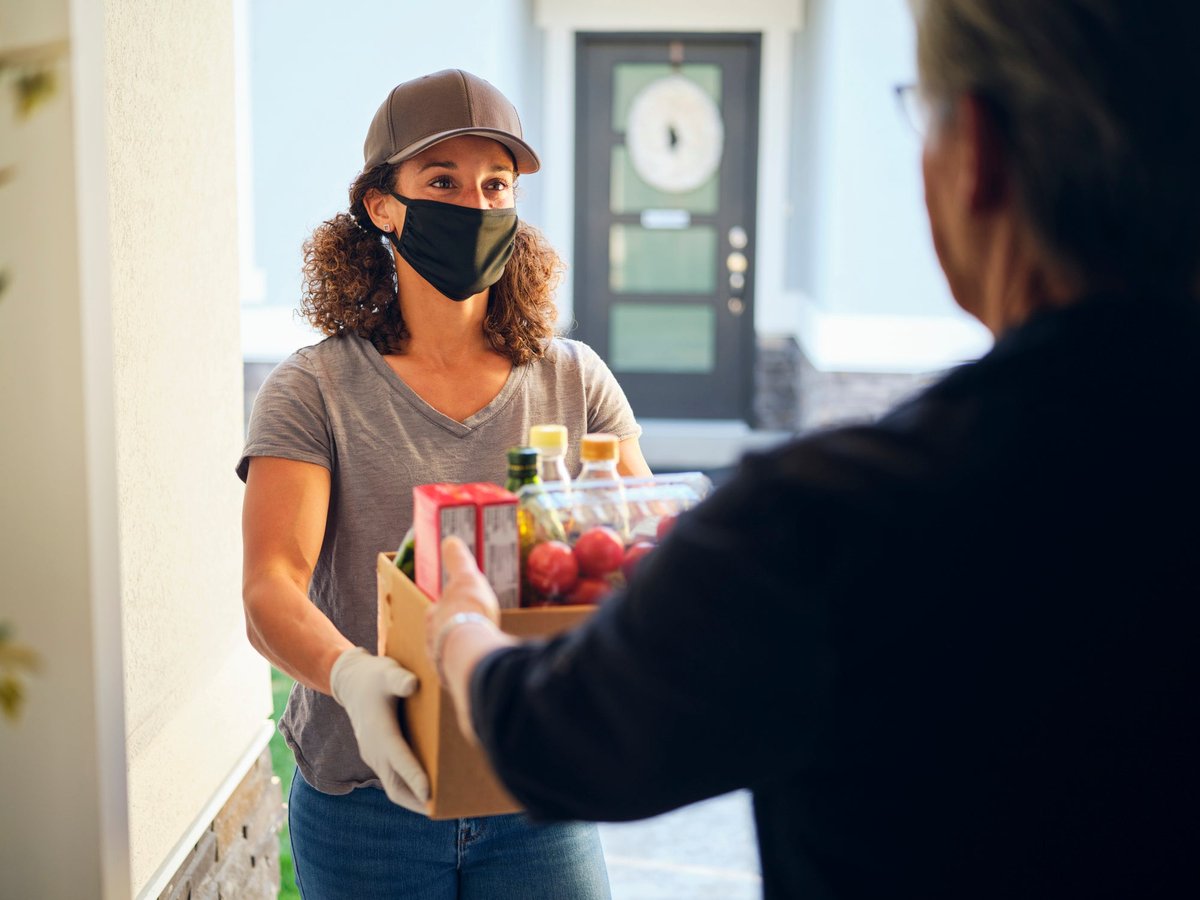 A delivery person drops groceries off at the home of a customer.