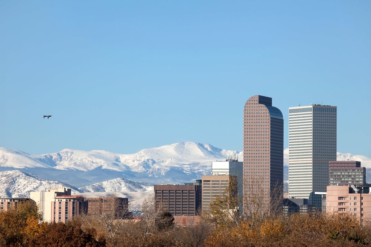 Downtown Denver skyline with mountains in background.