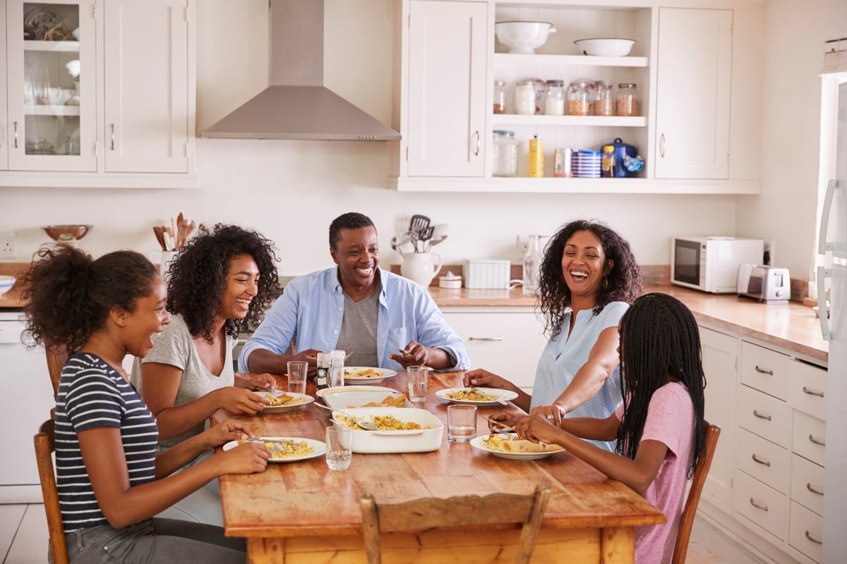 A smiling family eating breakfast together at the kitchen table.