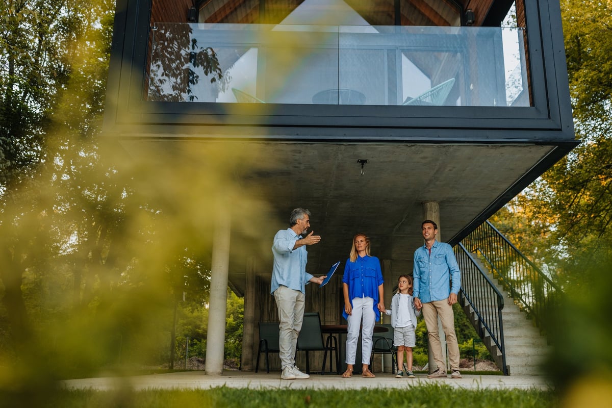 Family talking to realtor by extra modern home.