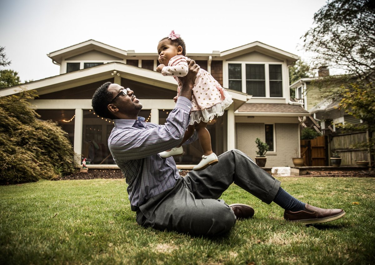 Father and toddler daughter play in home's backyard.