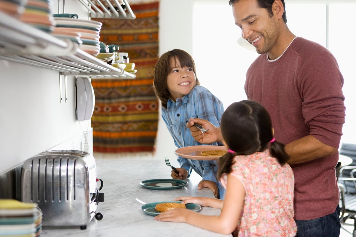 Father in kitchen with kids making breakfast