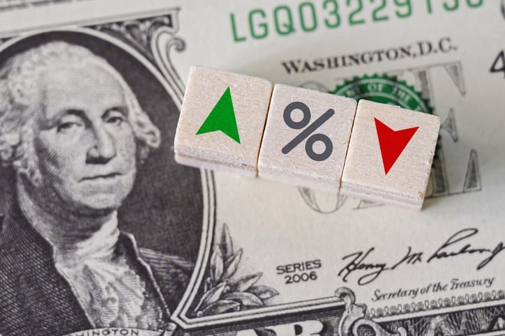 Blocks with up and down and percent signs on top of a dollar bill with George Washington showing.