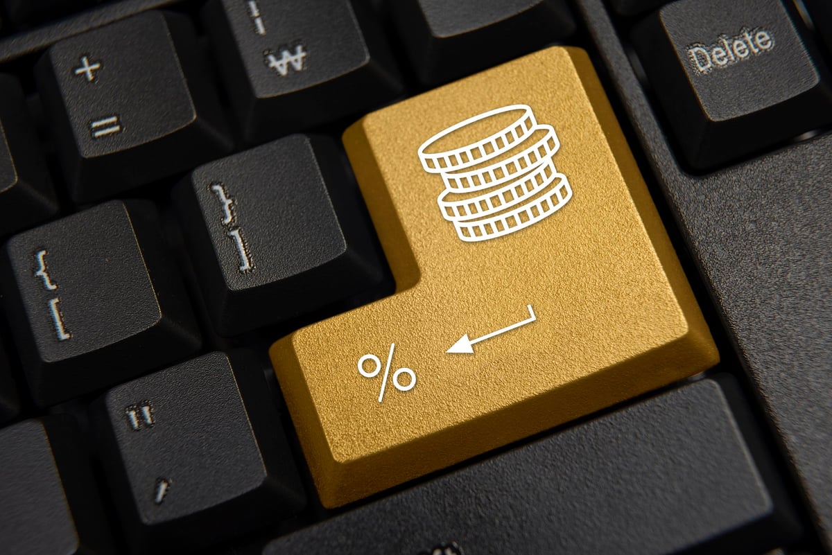 A computer keyboard featuring a golden return key marked with a stack of coins and a percentage sign.