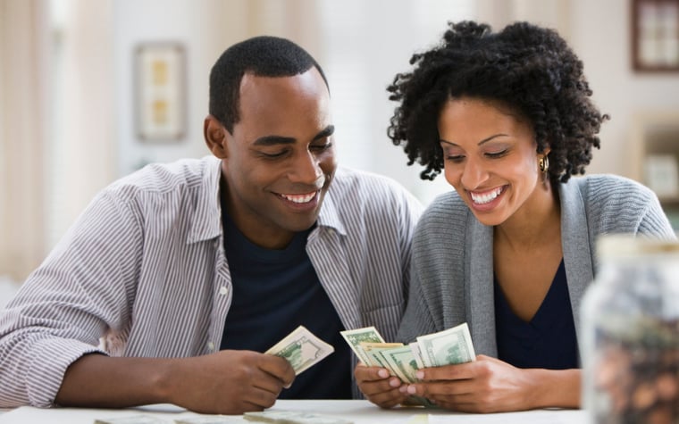 Un couple compte des billets d'un dollar ensemble à la maison.