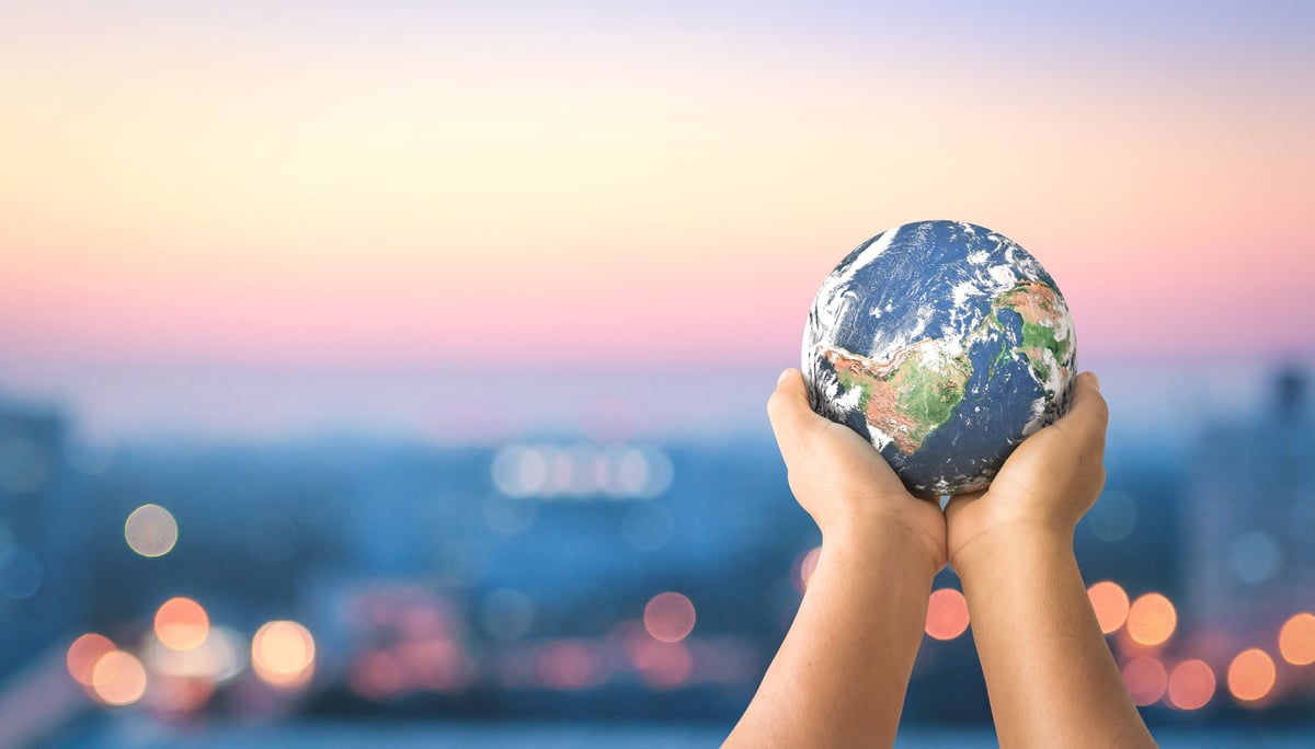A pair of hands raising forth a small-scale model of planet Earth.