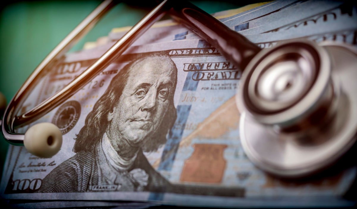 A stethoscope listening in to what's happening inside a stack of 100 dollar bills.