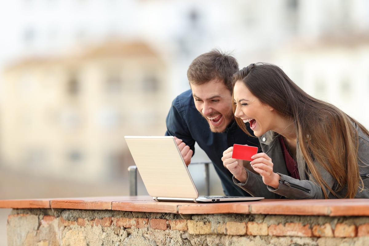 Young couple very excited about their credit card and what's on their computer screen.