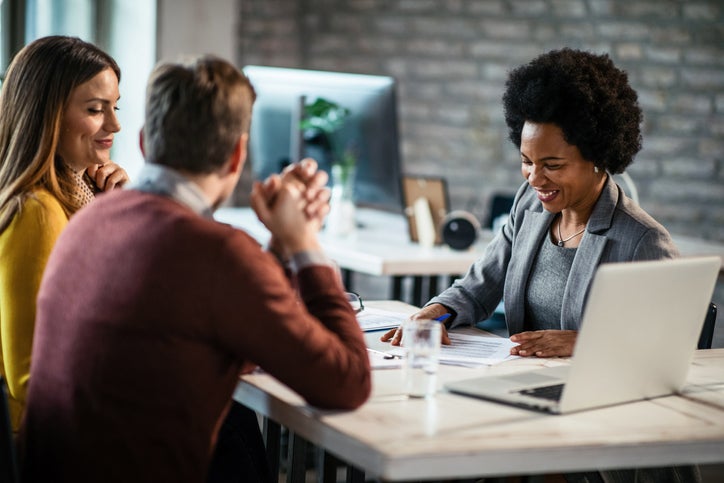Businesswoman helps couple with paperwork in an office