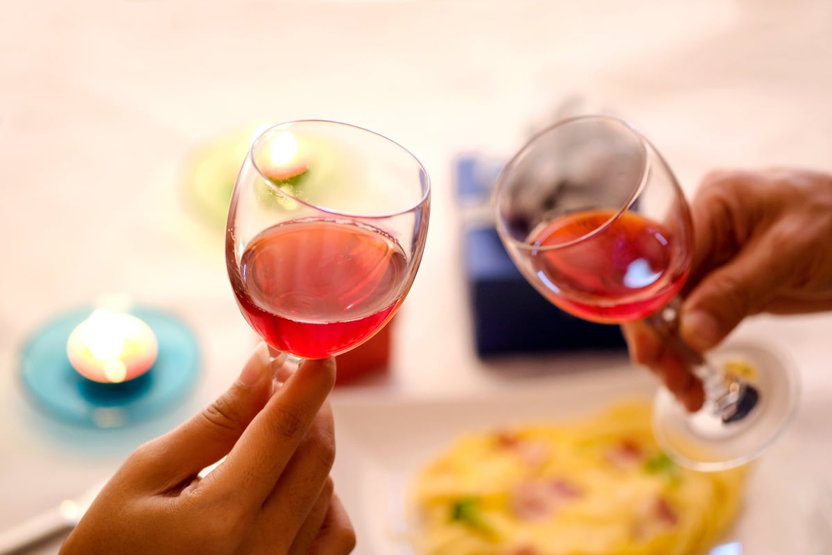 Hands clinking wine glasses.