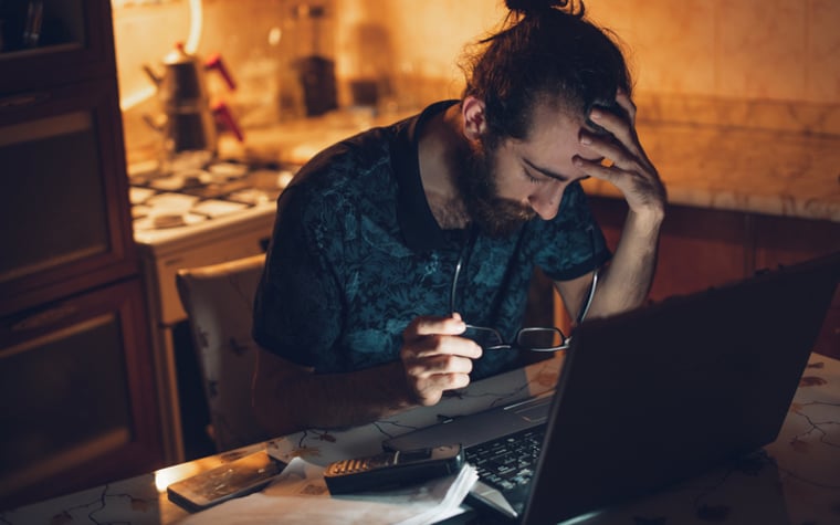 Frustrated man at desk with head in his hands.