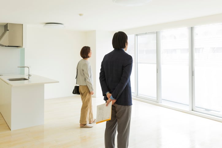 Two prospective buyers look out of window in new apartment.