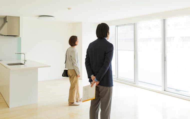 Two prospective buyers look out of the window in a new apartment.