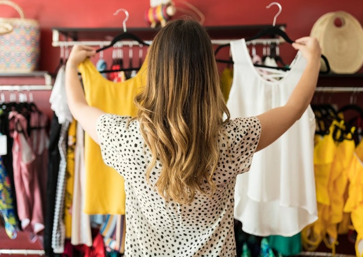 Woman shopping at a clothing store chooses between two shirts