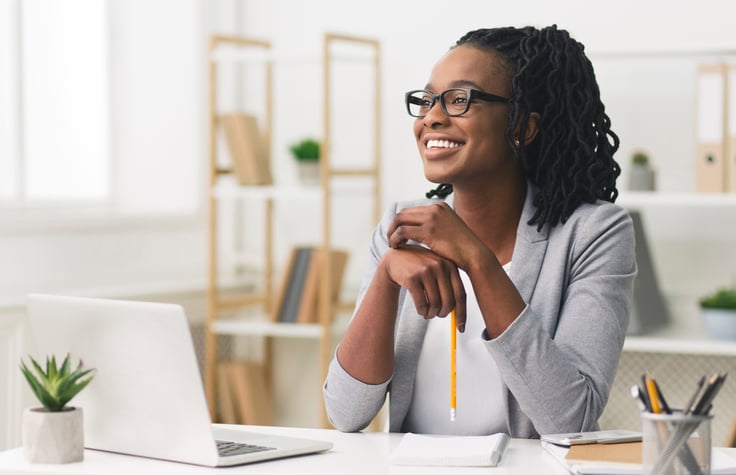 Happy woman at computer with pencil in her hand.