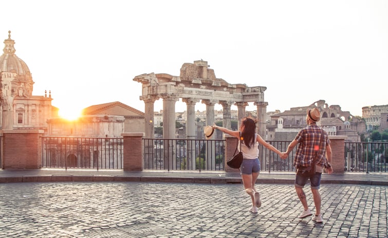 Young couple walking towards the Roman Forum in Rome at sunset.