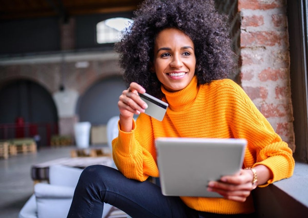 African American woman happily uses her credit card to make an online purchase.