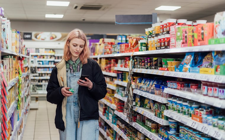 Person looking at mobile phone and shopping at convenience store