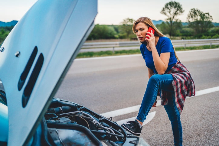 A woman uses her cell phone to call for help after her car breaks down.