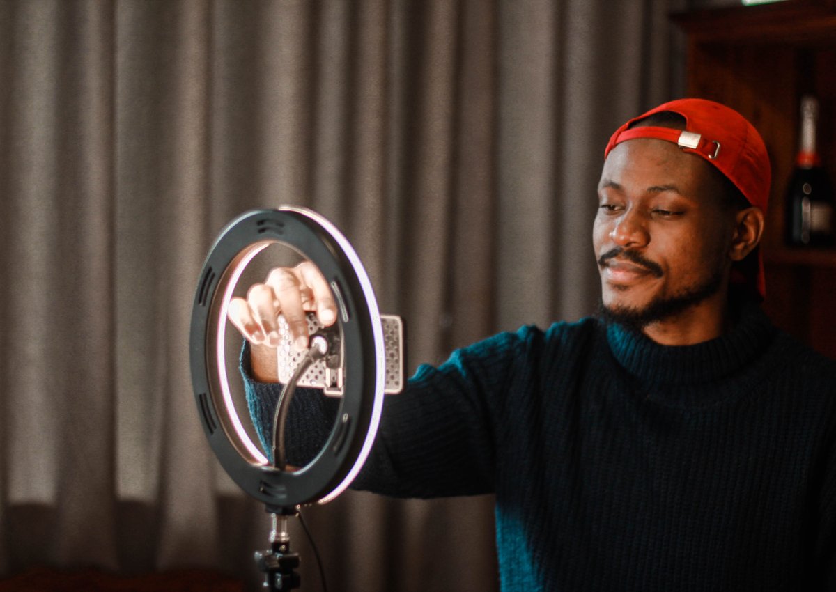 Someone vlogs using a smartphone and ring light.